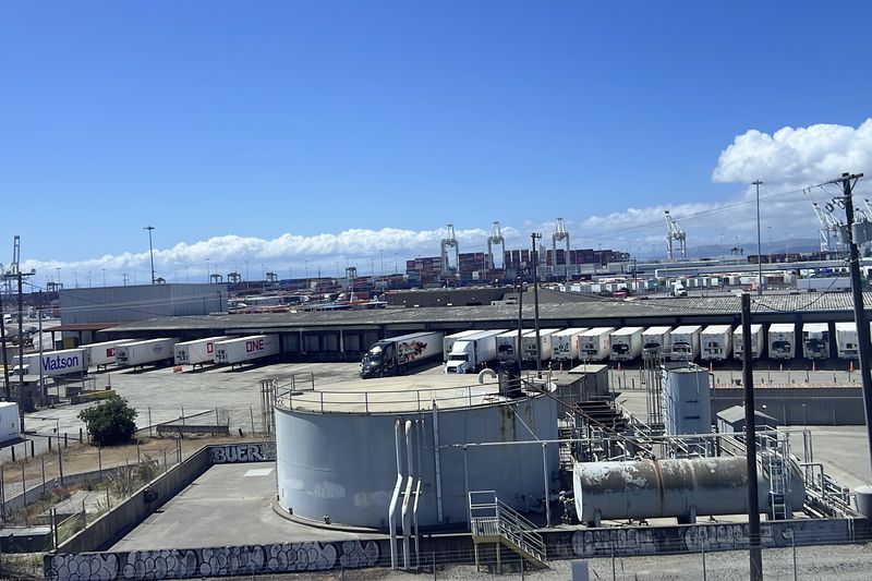 Shipping containers, trucking operations, and industrial storage tanks at the Port of Oakland on a clear day, West Oakland, California, May 2025