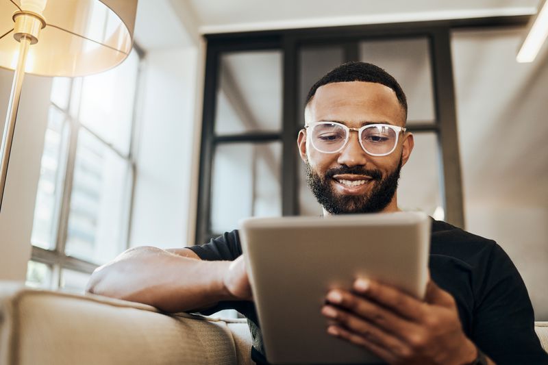 A man looks at his tablet and smiles 