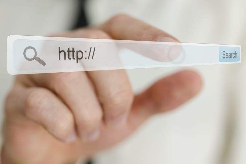 Businessman’s hand pointing at search bar on virtual screen