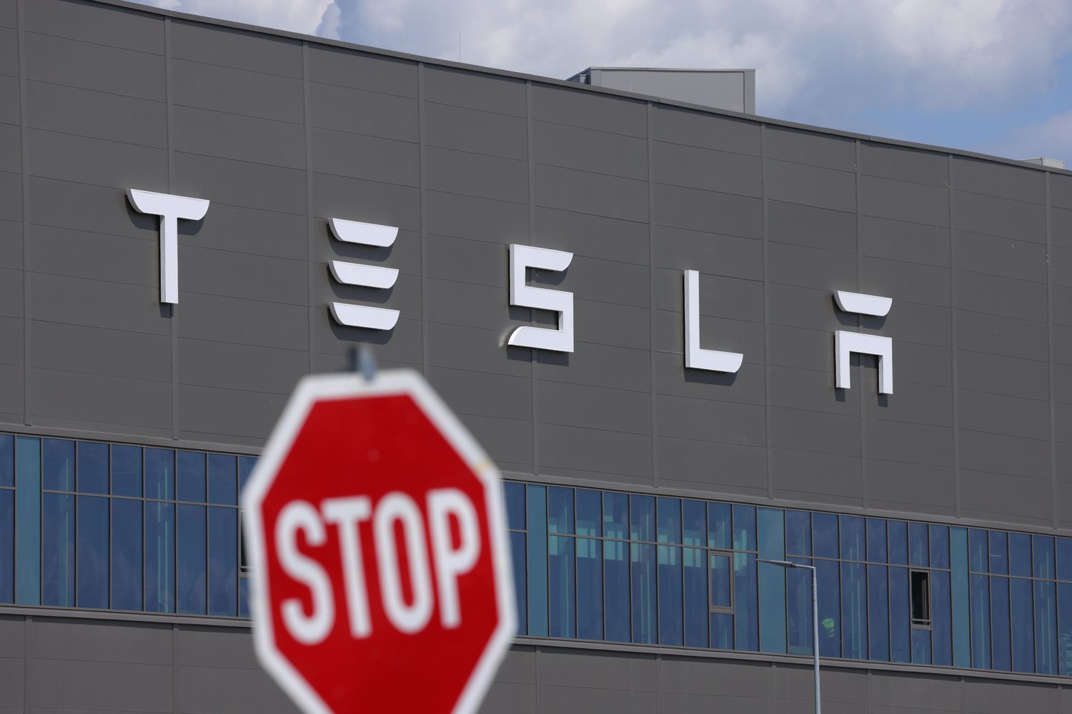 A stop sign stands near the Tesla logo at the Tesla factory on July 17, 2023 near Gruenheide, Germany.