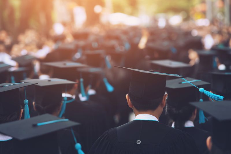 group of university students in line at graduation wearing gown and cap