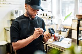 A barista writing a name on a coffee cup