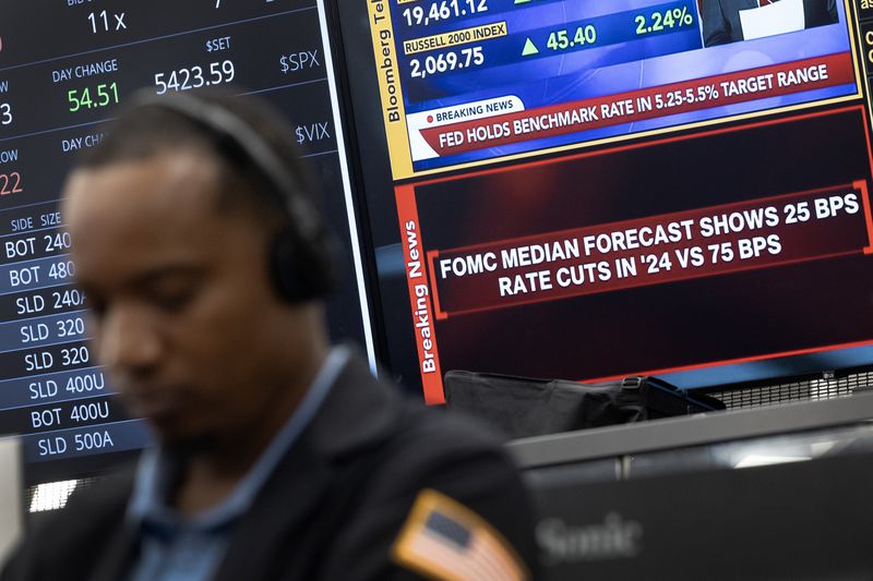 A trader sits in front of TV screens displaying information about the Fed's rate cut announcement.