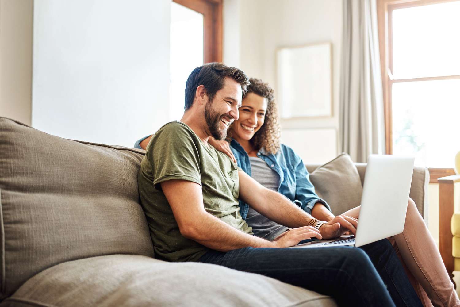 Shot of a happy young couple using a laptop together on the sofa at home.