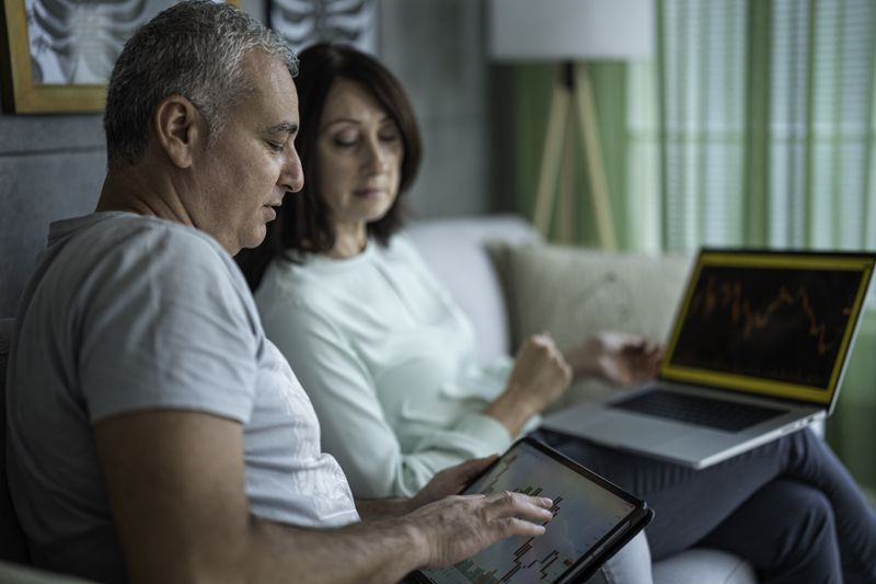 A couple sitting next to each other on a laptop, studying charts.