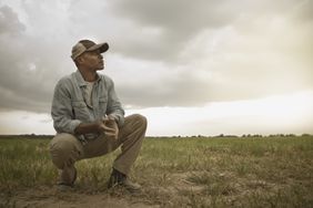 A farmer watches the horizon for weather while sitting in his field. 