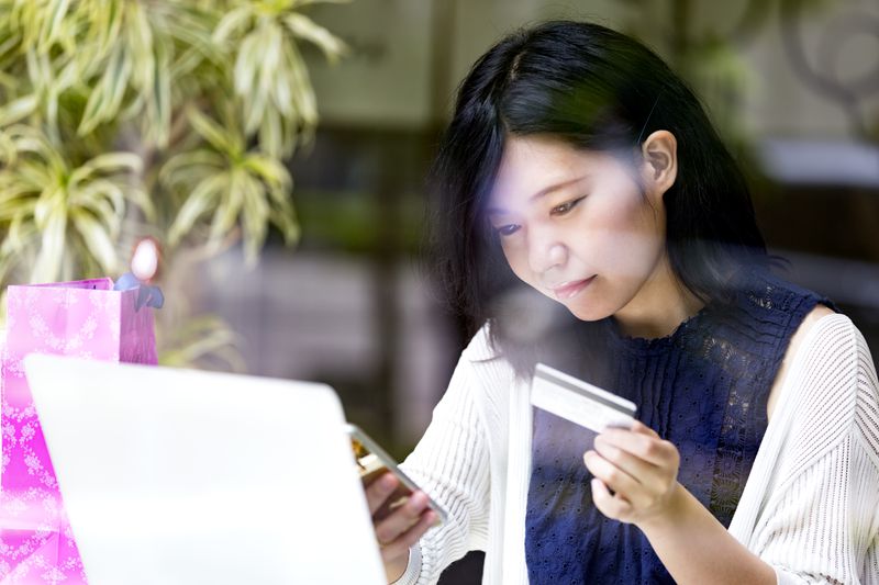 Japanese girl using her smartphone and credit card to make an online payment