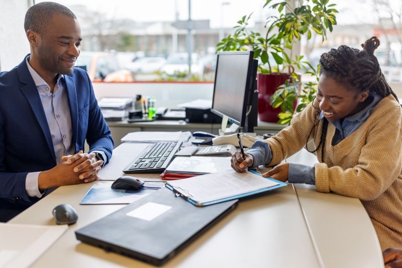 A happy person signs a rental agreement contract that will allow them renew their lease at the same rate after the end of the current term.