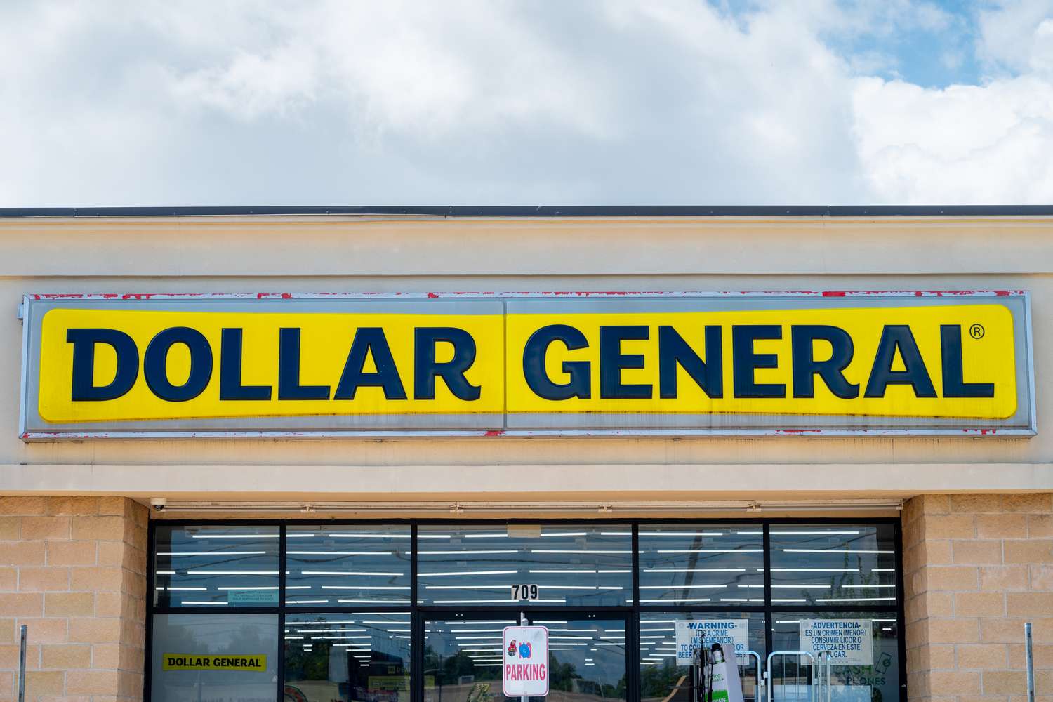 The yellow and black Dollar General sign is seen above the entrance to a store.