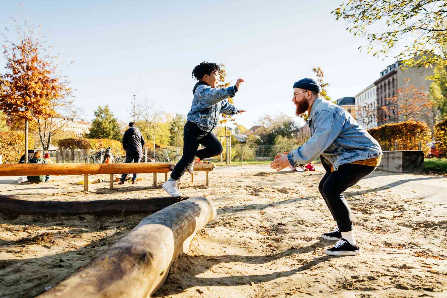 A young boy leaps into his father's arms in a playground.