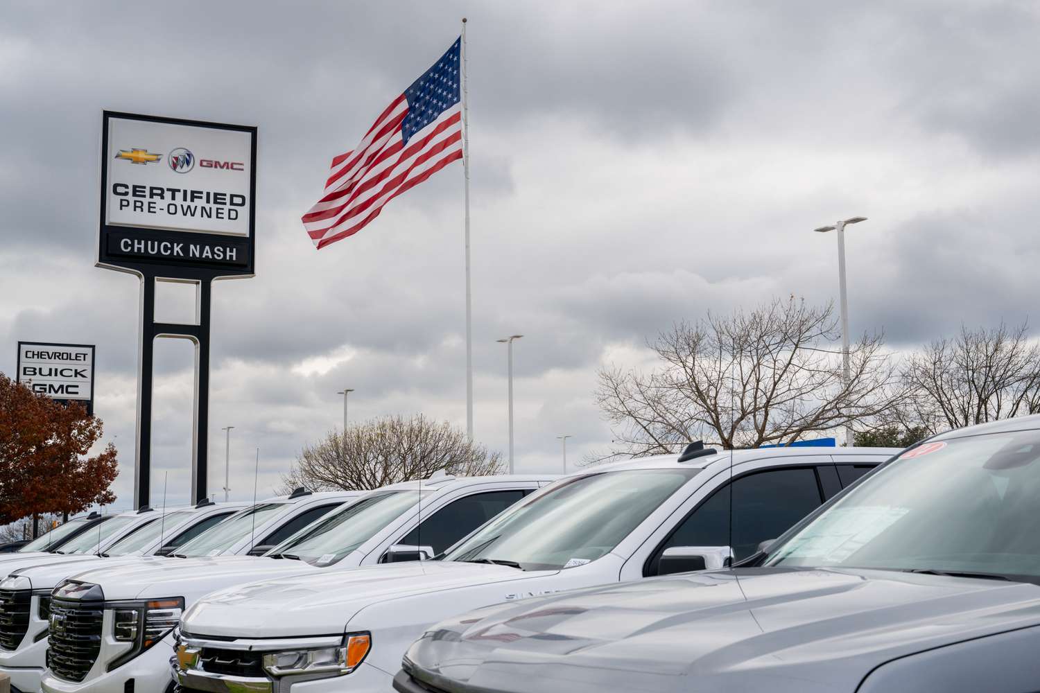 Vehicles sit in a dealership lot.