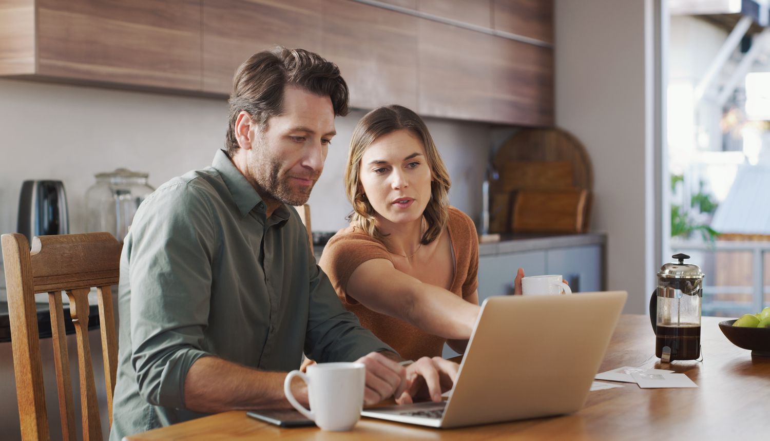 A couple looks at a laptop computer, serious expressions