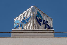The blue Pfizer logo is seen on a sign above a gray building.
