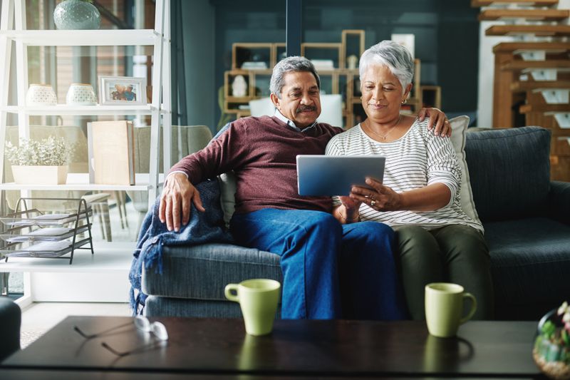 Older couple sitting on their sofa and looking at online bank rates on a tablet
