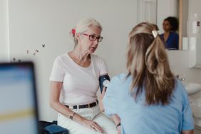 Older woman getting her blood pressure checked by a health care worker