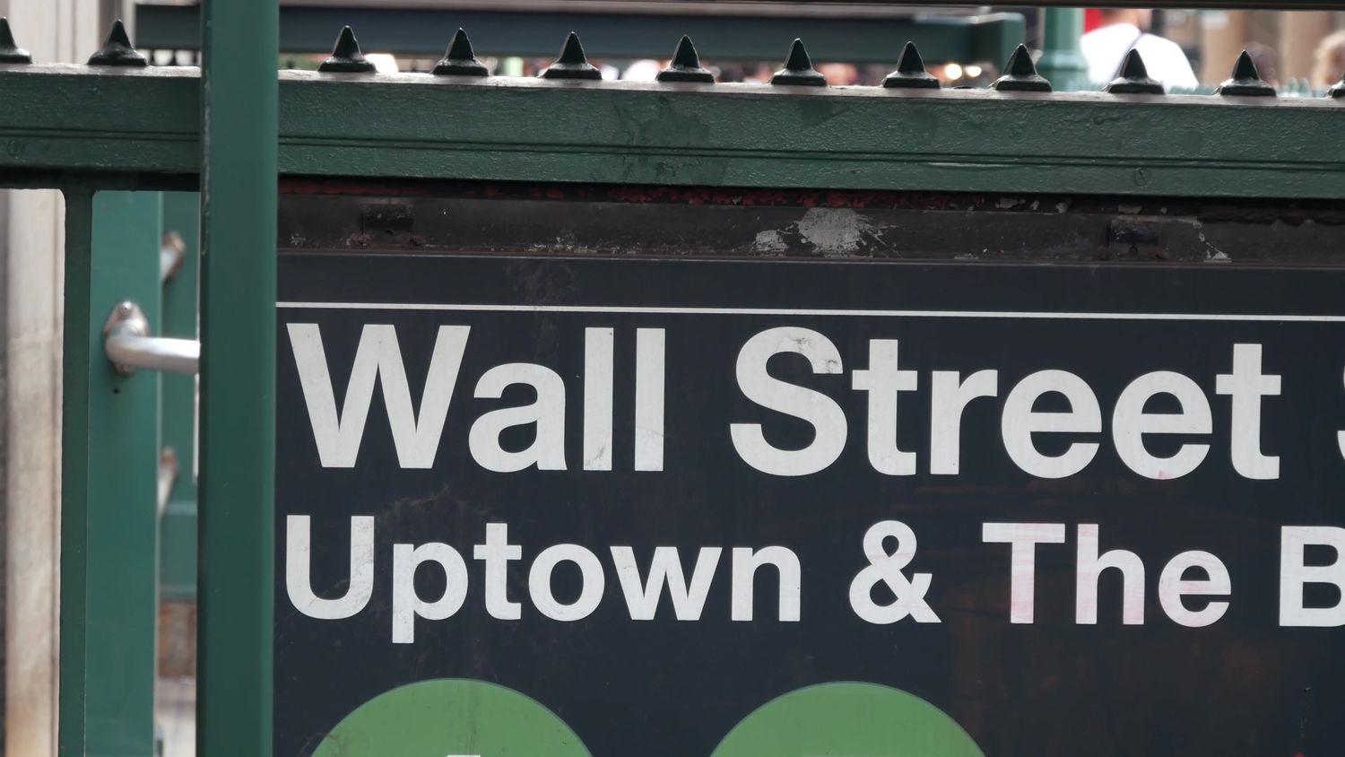 A New York City subway sign reading "Wall Street."