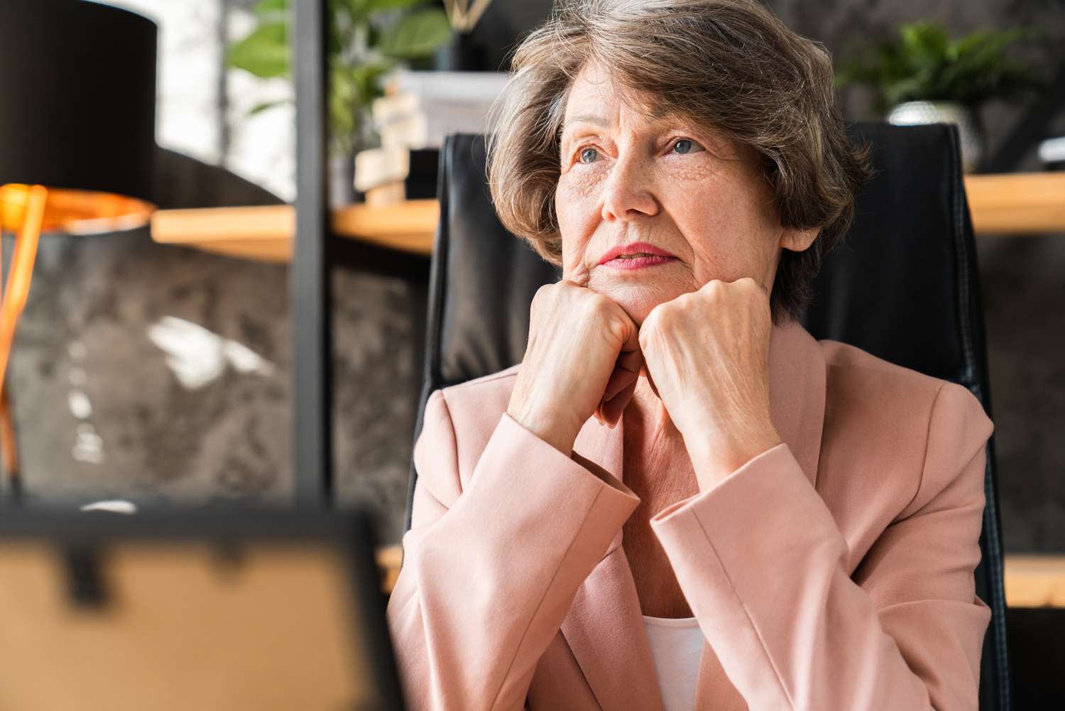 Older woman with her fisted hands on her chin, looking contemplative