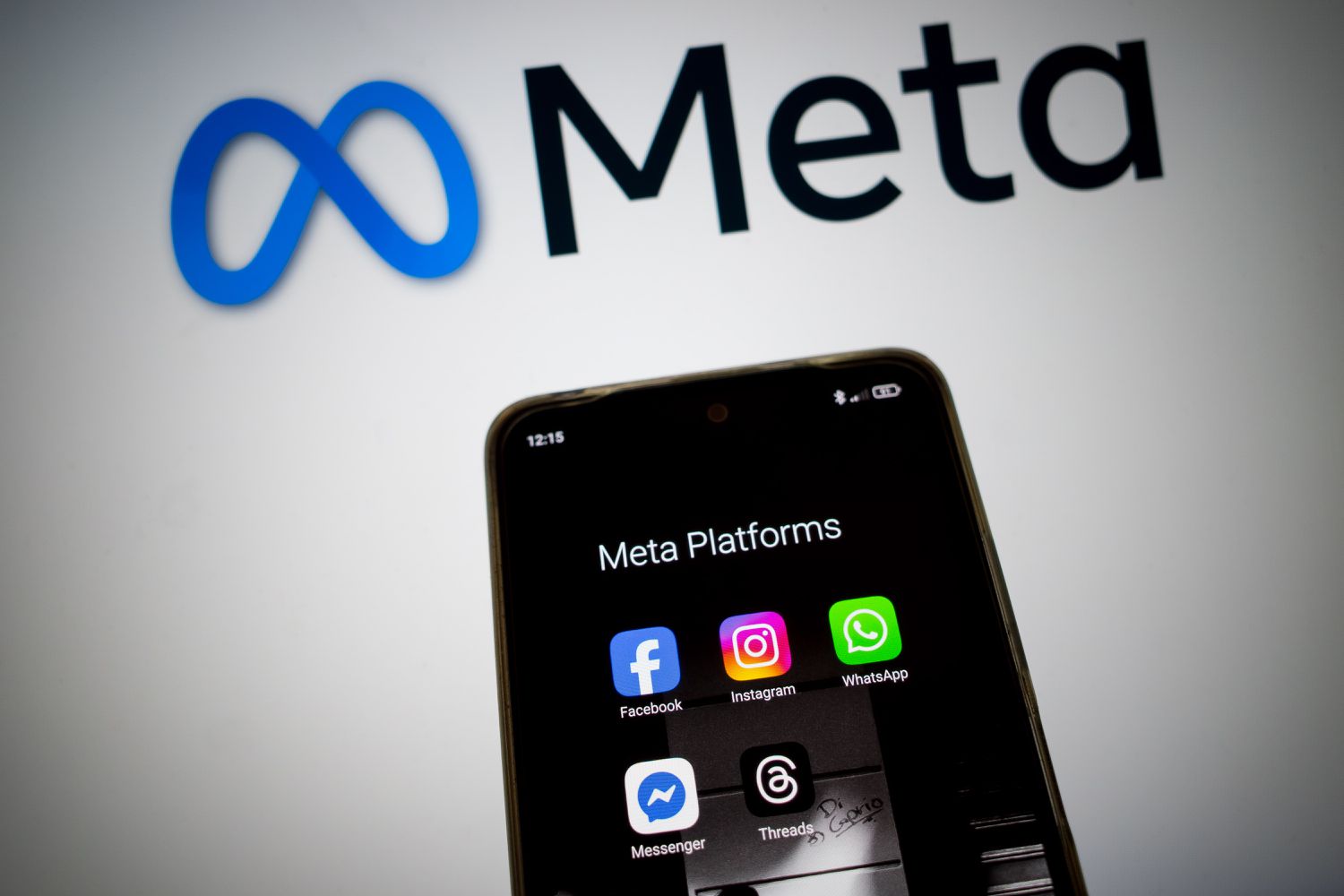 The Meta logo above a mobile device that displays the logos of several social-media apps owned by the company.