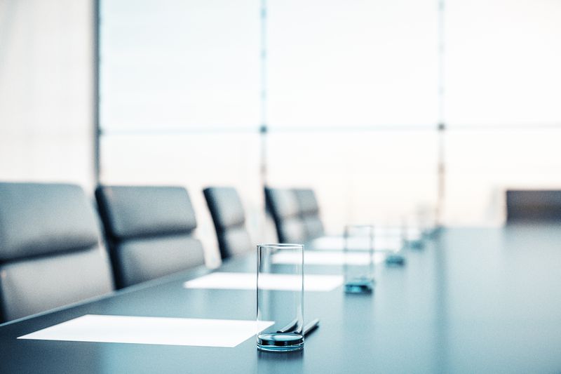 close up of a conference room with armchairs, and glasses, papers, and pens on a table