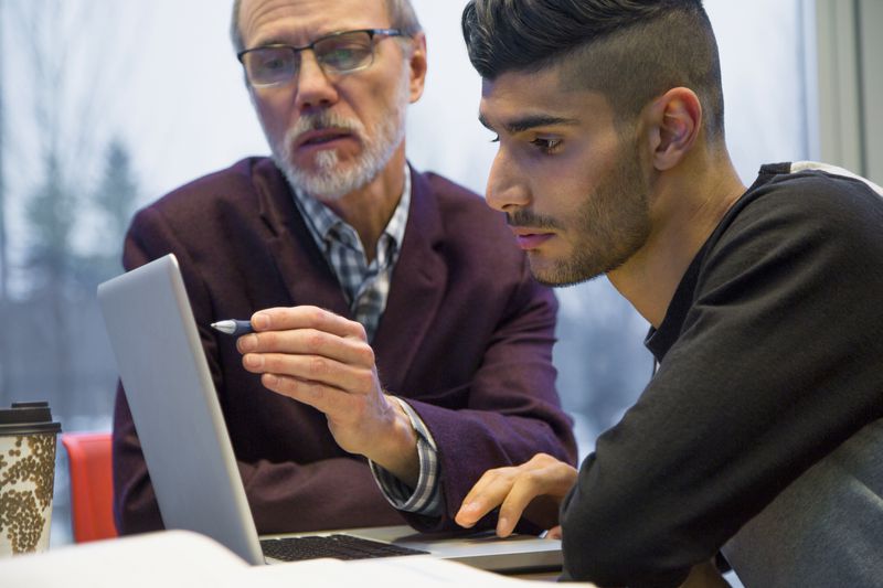 Professor and college student at laptop.