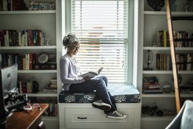 Mature woman on window seat reading a book