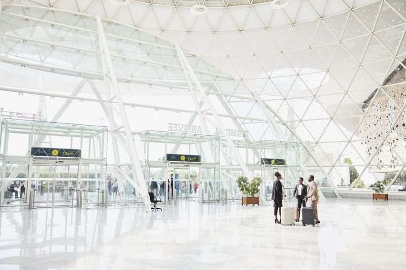 Extreme wide shot of business colleagues in discussion in airport arrivals terminal after flight