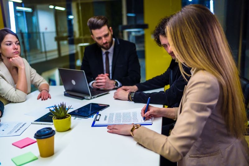 People sitting in a meeting room and signing Up-Front Mortgage Insurance (UFMI) contract.