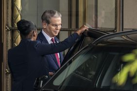 A person holds the door to a car open for Treasury Secretary Scott Bessent.
