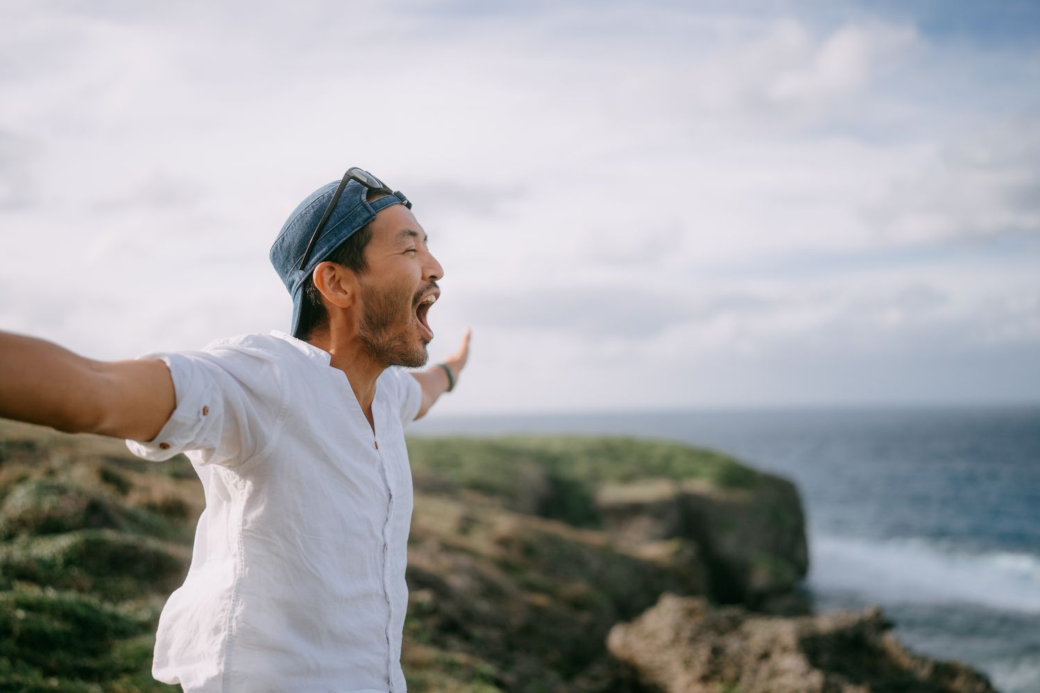 Man yelling on top of cliff by sea, Japan