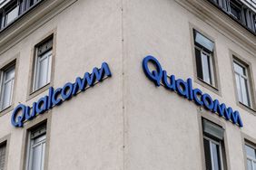 The blue Qualcomm logo is seen on two sides of a tan building.