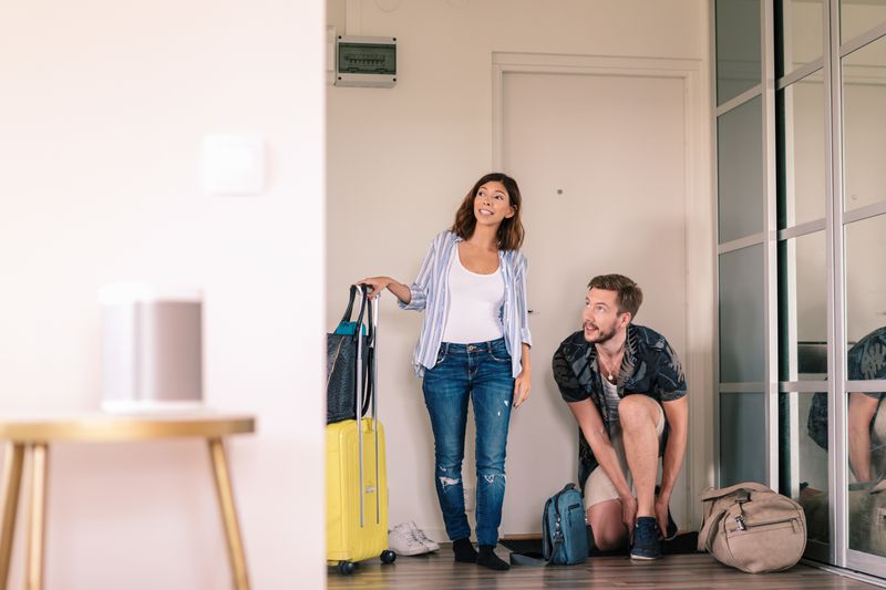 Excited couple with luggage arriving at the doorway of their Airbnb.