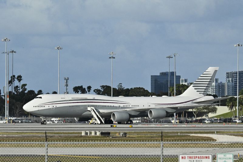 A large passenger jet parked at an airport with stairs extended, cityscape in the background