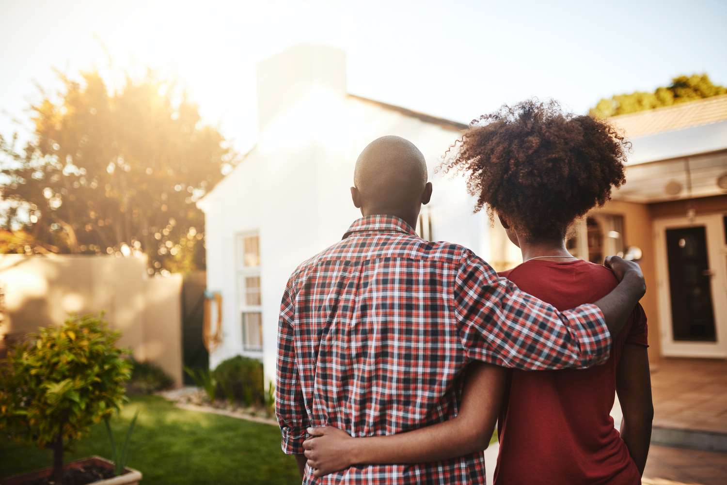 a young couple standing outside looking at a house