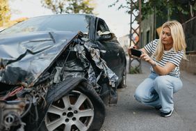 A driver takes a photo of a damaged car after an accident