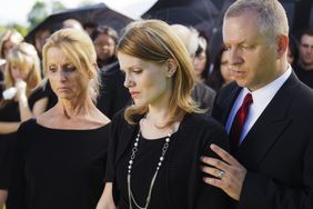 A grieving family standing graveside at a funeral.