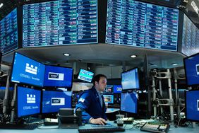 A trader works on the floor of the New York Stock Exchange surrounded by screens with stock market data