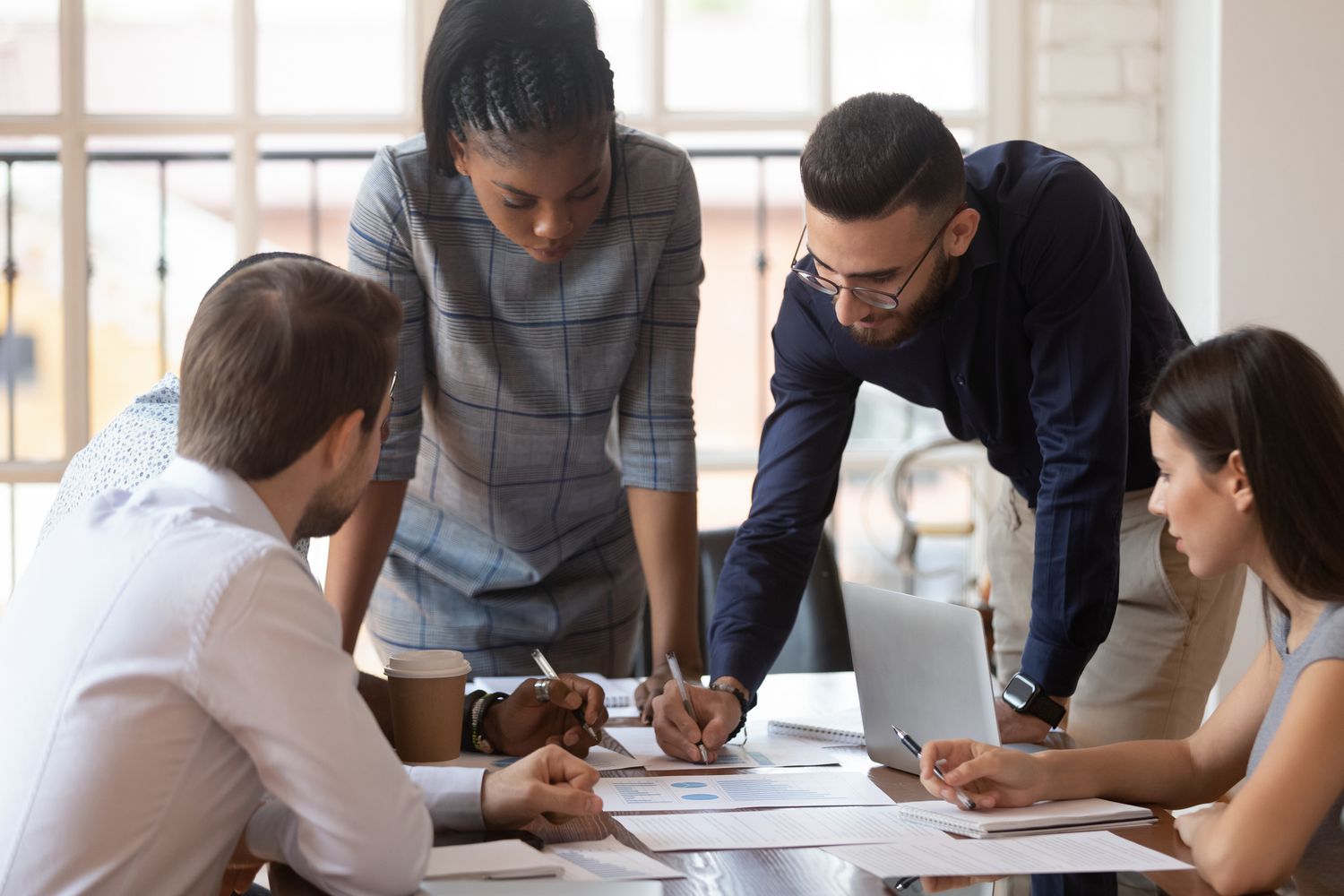 focused corporate team working at a desk in an office with papers and laptops
