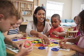 A teacher interacting with children during a classroom activity at a table