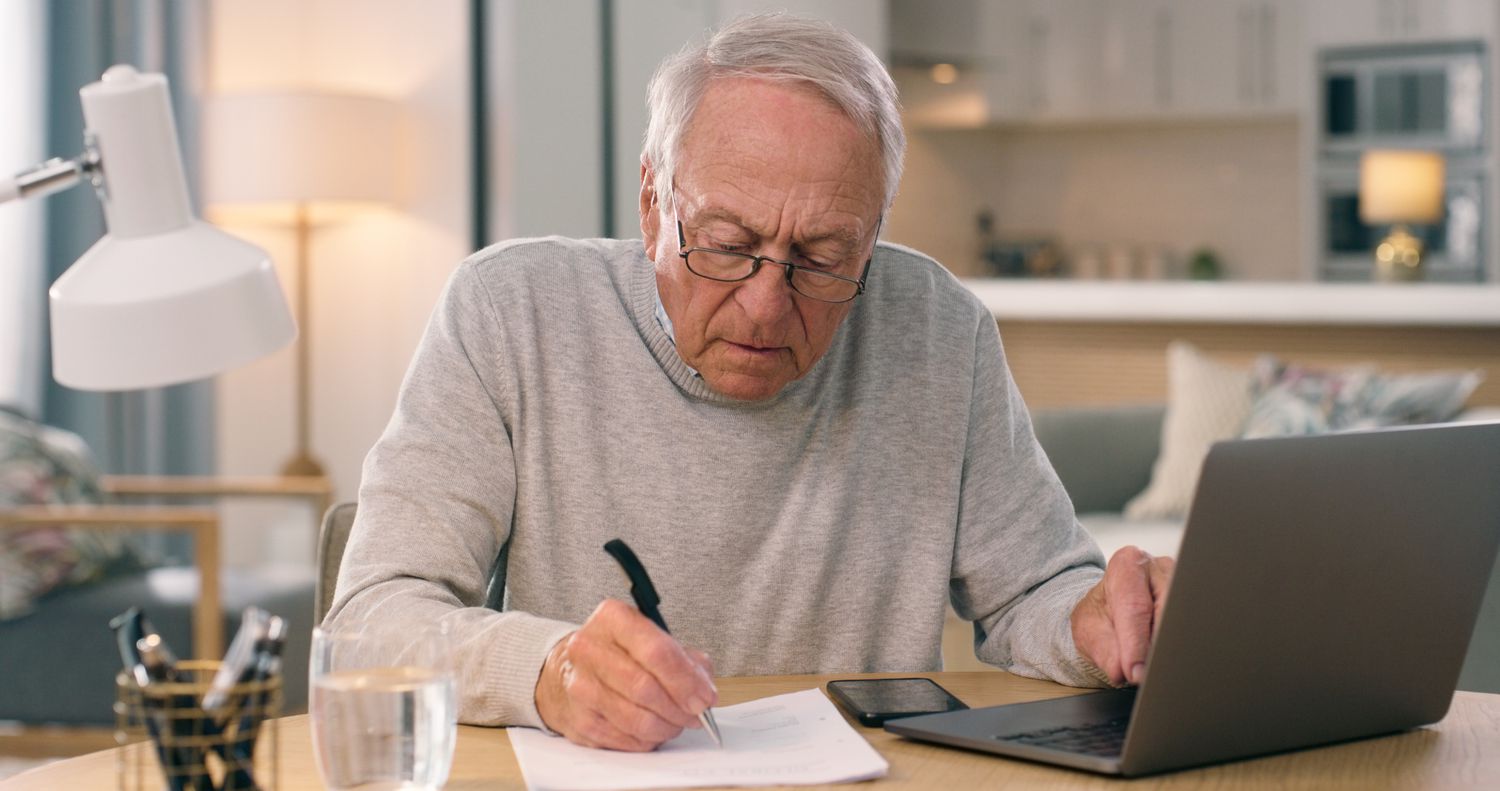 An annuitant uses a laptop computer to check statement balances and jots notes onto a piece of paper.