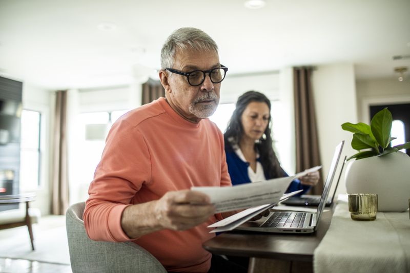 Two individuals reviewing documents at a desk with a laptop