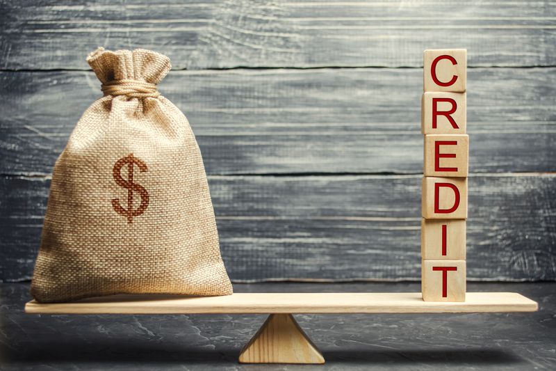 Money bag and wooden blocks with the word Credit on the scales. The concept of a successful loan. Correction and formation of credit history. Refinancing credits. Favorable interest rates.