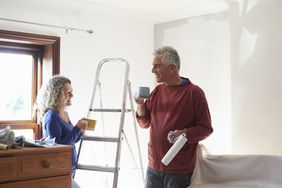 A couple takes a coffee break from painting a room in their home.
