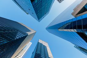 looking up at skyscrapers in manhattan with a blue sky