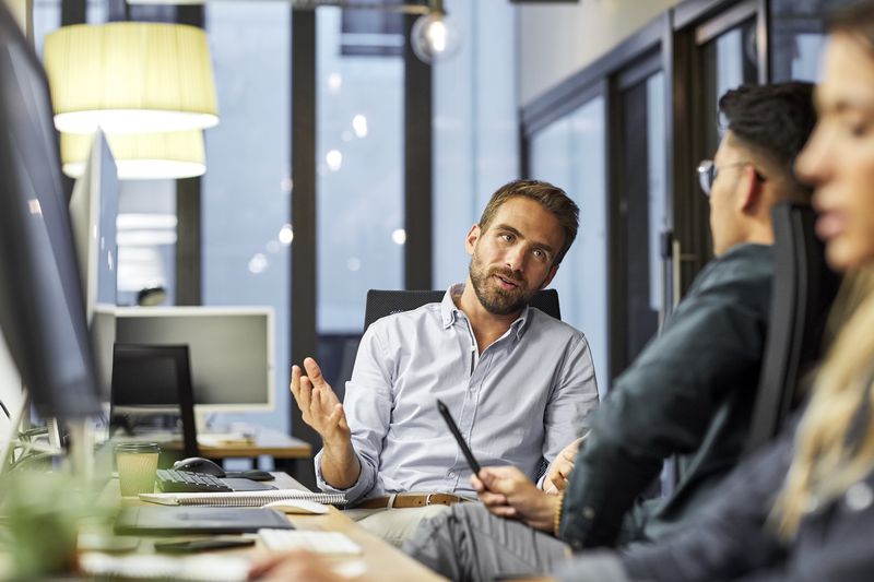 A businessman explaining colleague while sitting at desk.
