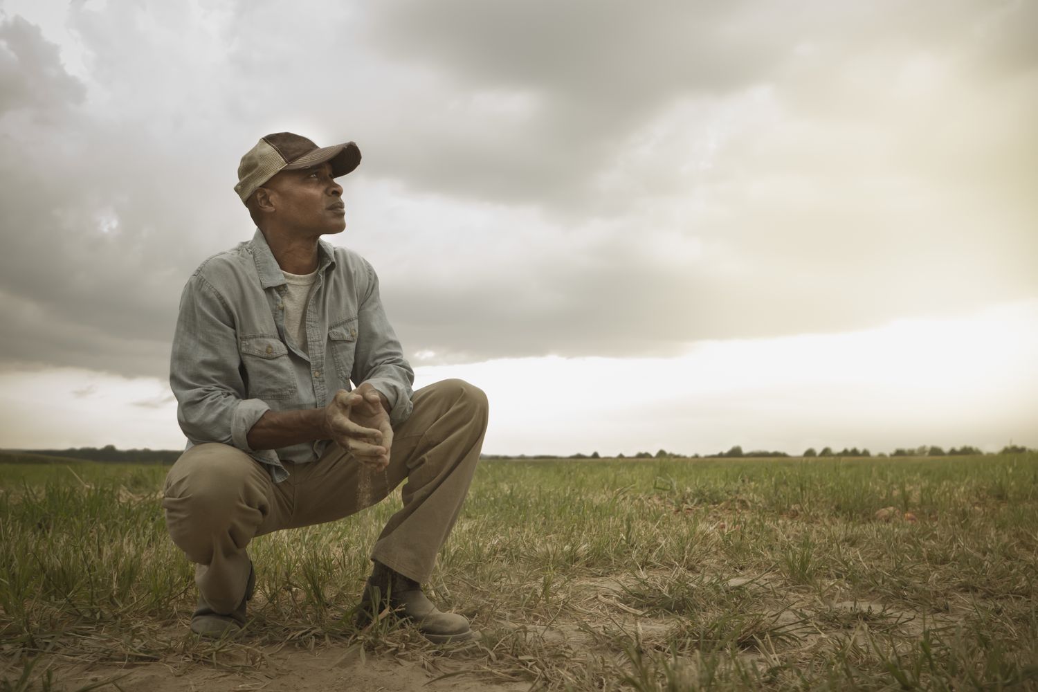 A farmer watches the horizon for weather while sitting in his field. 
