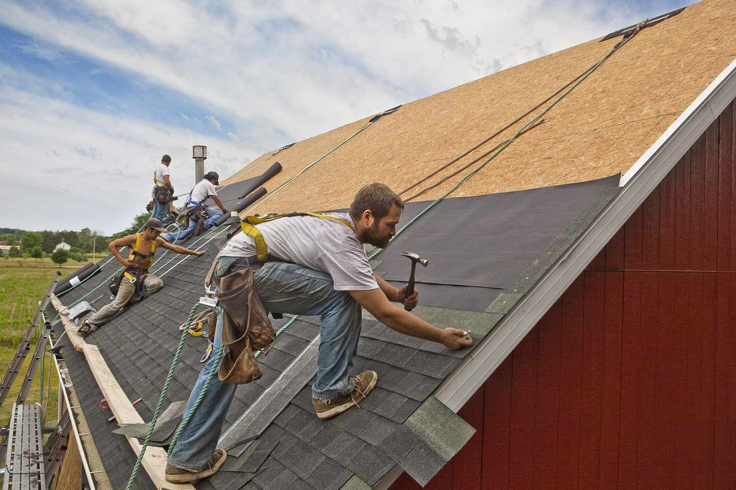 Workers install a roof on a rural building