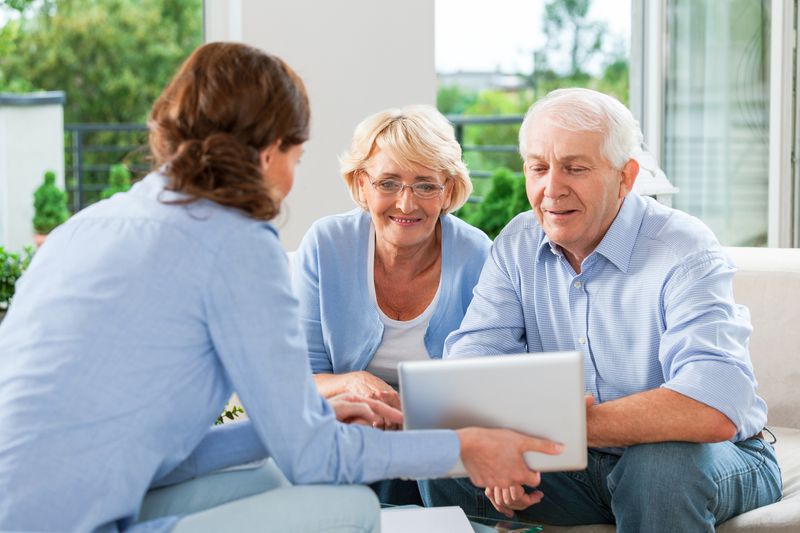 A couple having meeting with financial advisor or insurance agent at home.