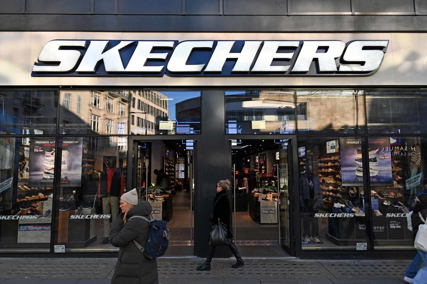 People walk by the front of a Skechers store on the streets of London.