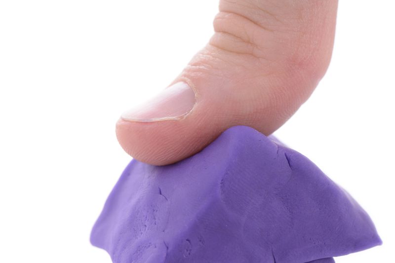 A thumb pressing on a purple dough house
