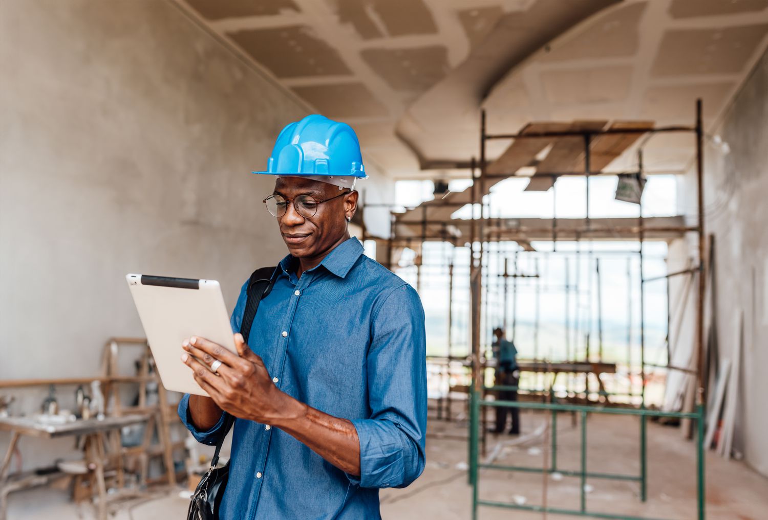 An engineer reviews customer specifications while standing in an unfinished office space surrounded by scaffolding and work benches.